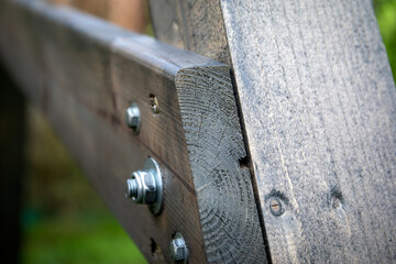 Detailed view of a wooden beam joint connected with bolts and metal fasteners, showing carpentry, construction
