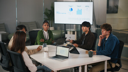 Diverse group in modern office collaborates on startup project teamwork, sharing ideas and analyzing data visualization on screen for business growth and innovation
