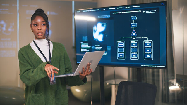 Diverse team member presenting office teamwork strategy for startup project using digital screen and laptop in modern workspace with confident expression