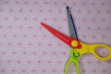 Colorful craft scissors with zigzag blade on Japanese patterned paper background