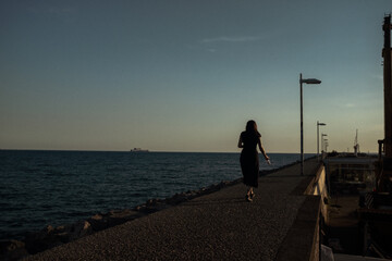 Fototapeta premium woman walking on the pier at sunset