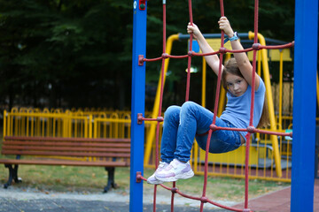 Obraz premium Girl climbing on playground ropes