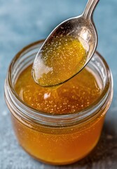 Amber syrup pouring from spoon into jar