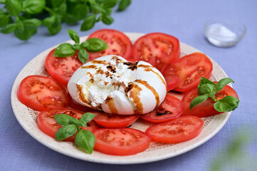 Italian burrata with tomatoes and basil on a plate close-up