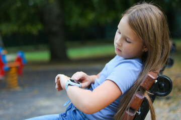 Young girl checking smartwatch in park