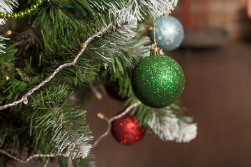 Close up of a decorated Christmas tree with glitter balls, garland, and lights. Festive interior for the holiday season.