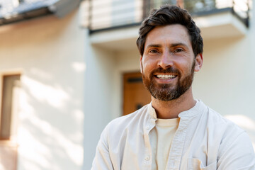Portrait of smiling homeowner standing in front of his house
