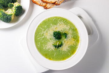 Warm and comforting creamy broccoli soup served in a bowl, garnished with parmesan cheese and...
