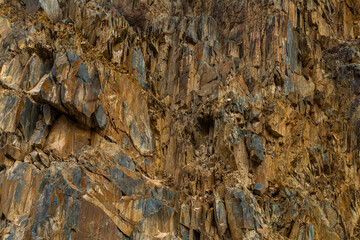 Rugged rock formation stands majestically in a mountainous Kyrgyzstan under bright daylight.