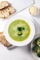 Warm and comforting creamy broccoli soup served in a bowl, garnished with parmesan cheese and...