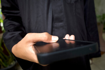 Close up of a child hand using a black mobile phone, shallow focus