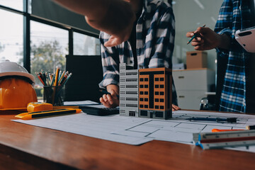 Construction and structure concept of engineer working drawing on blueprint meeting for project working with partner on model building and engineering tools in working site, construction concept.
