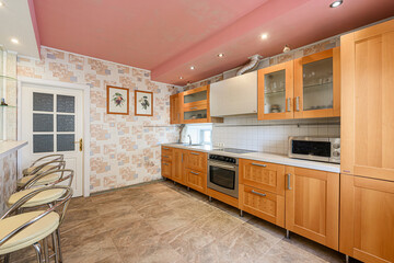 kitchen featuring light wood cabinetry, tile floors, and a unique pink ceiling. Bar stools are visible near a white door