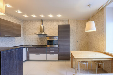 Modern kitchen with brown cabinets, island, stainless steel oven, and floral wallpaper. Warm...