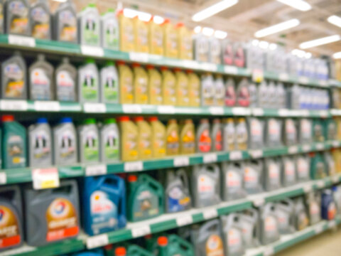 Blurred colorful motor oil bottles on shelves in supermarket as background