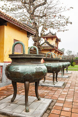 Row of ancient bronze dynastic urns on tiled terrace at Hue Imperial City Vietnam