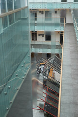 Modern multi story office building interior showing spacious atrium, glass railings, open walkways,...