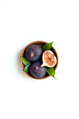Fresh ripe figs with leaves on a wooden bowl top view on a white background