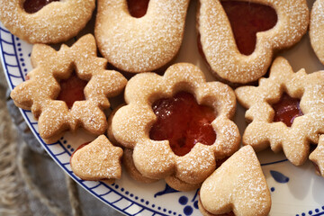 Closeup of traditonal Linzer Christmas cookies filled with marmalade and dusted with sugar on a plate