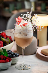 Fruit-infused dessert drink. A dessert drink with whipped cream and strawberries sits on a table...