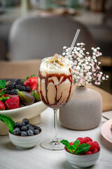 Berry flower dessert drink. A colorful dessert drink with whipped cream sits beside fresh berries and a lovely flower arrangement.
