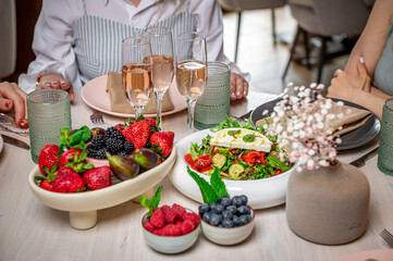 Brunching with friends. Friends gather for a brunch featuring fresh fruits, salads, and sparkling drinks in a modern dining space.