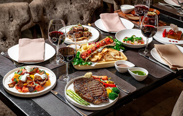 Chic dinner with wines and dishes. A lavish table with gourmet meals, steak, vibrant sides, and red...
