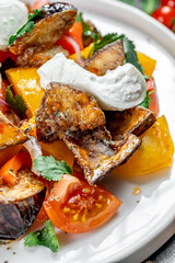 Creamy colorful veggie salad. A vibrant salad featuring roasted vegetables, fresh tomatoes, and a dollop of creamy dressing garnished with herbs.
