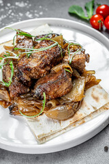 Grilled meat with onions. Juicy grilled meat served on a bed of caramelized onions, garnished with herbs and fresh tomatoes on the side.