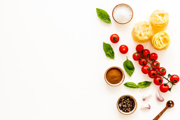 Fettuccine with ingredients for cooking pasta - tomatoes and basil with garlic - on a white background, top view. Flat lay