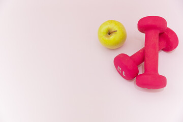 Pink Kilogram Dumbbells On Light Pink Background with green apple, Space For Text, Space For Logo, Healthy Lifestyle