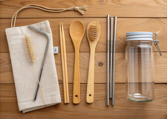 Minimalist flat lay of sustainable kitchen items, wooden spoons, metal straws, reusable containers, and linen cloth,