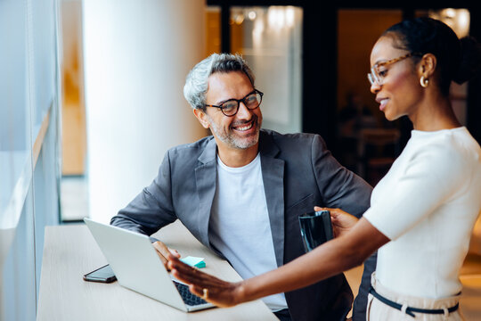 Professional coworkers having a discussion while working at a computer in an office