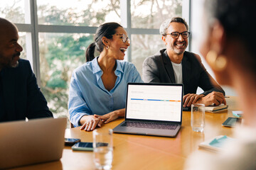 Business professionals laughing during a meeting at a conference table