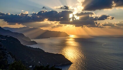Dramatic sunset over a coastal landscape, showcasing dramatic clouds, golden light, and rugged mountains meeting the sea.