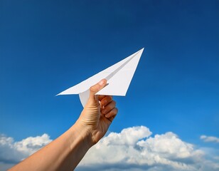 close up photo of hand hold a white paper airplane with a blue sky background