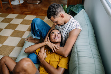 Happy male gay couple relaxing together on a comfortable living room sofa