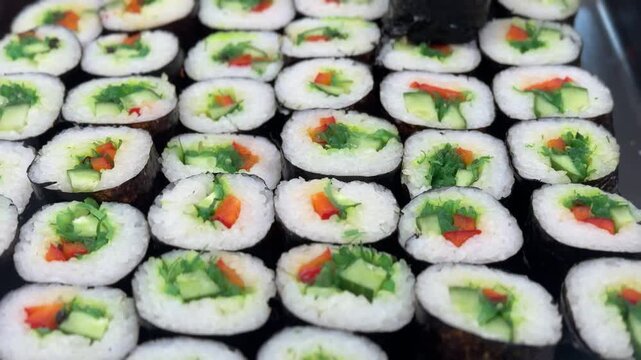 Variety of Freshly Prepared Sushi Rolls Beautifully Arranged on Display for Patrons. Exquisite and vibrant array of sushi rolls brilliantly showcasing various ingredients with artistic presentation.