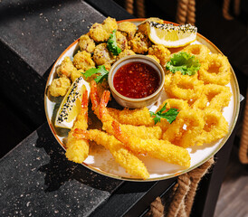 Fried seafood platter with shrimp, calamari, and dip in a lively setting