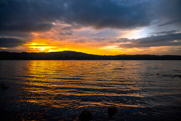 Pre-sunrise colours reflected in a lake and and clouds with distant hills, Lake Windermere, Cumbria, England 
