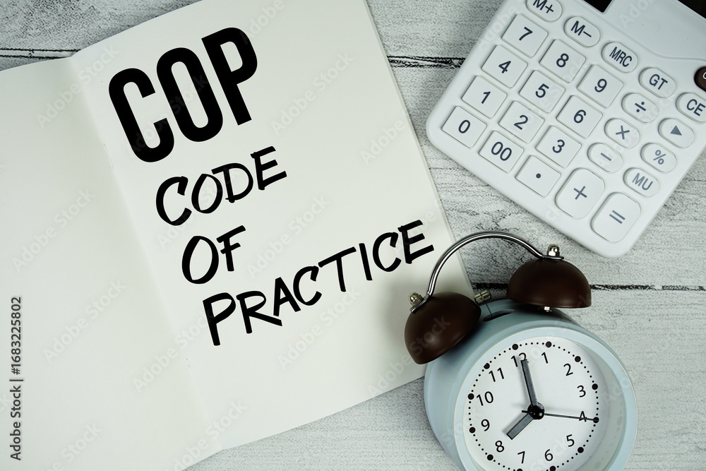 Poster cop code of practice text on paper notebook page with alarm clock and calculator on wooden backgroun
