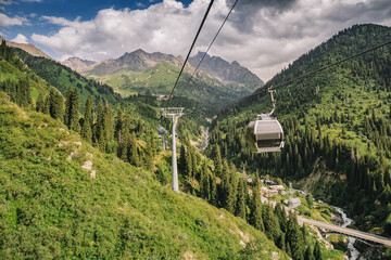 Cable car gliding over a lush green valley in the Tian Shan mountains, showcasing stunning scenery near Almaty, Kazakhstan © EdNurg