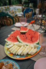 Outdoor summer dining: assorted fruits and snacks on a festive table.