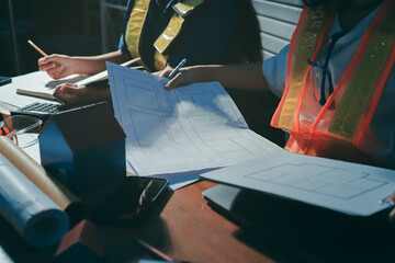 Closeup of team of industrial engineers meeting analyze machinery blueprints consult project on table in manufacturing factory. Working in manufacturing plant or production plant.