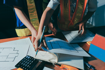 Closeup of team of industrial engineers meeting analyze machinery blueprints consult project on...