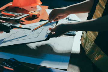 Closeup of team of industrial engineers meeting analyze machinery blueprints consult project on table in manufacturing factory. Working in manufacturing plant or production plant.