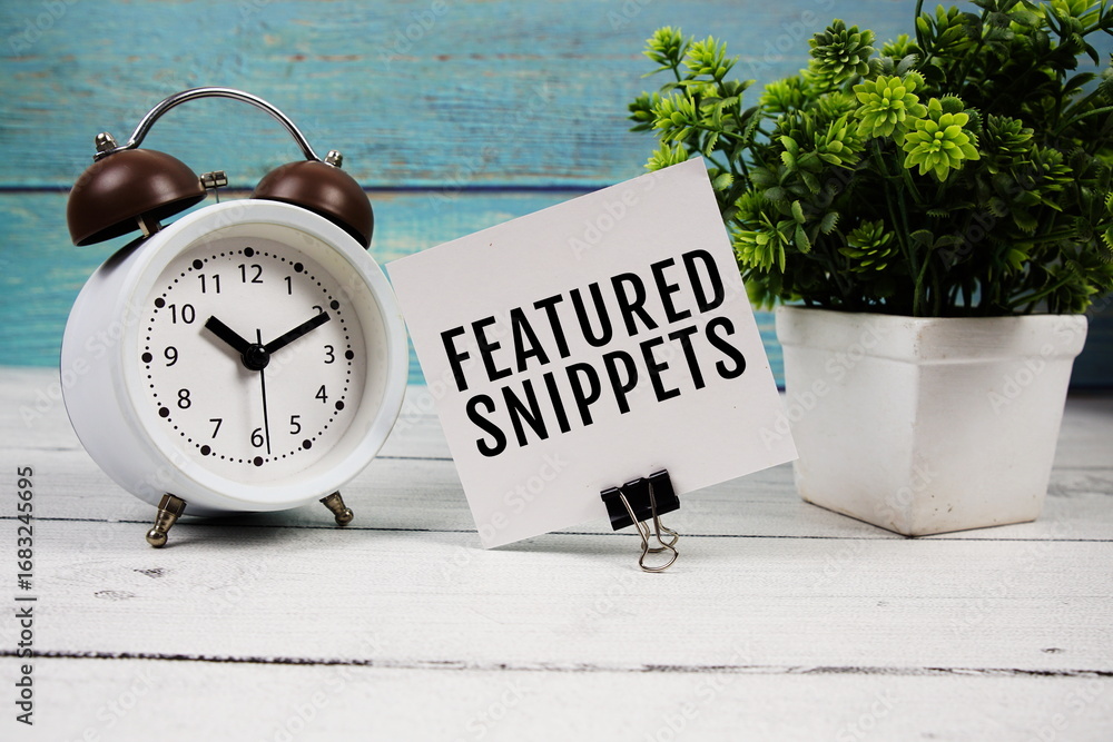 Poster featured snippets text written on paper card with alarm clock on wooden background
