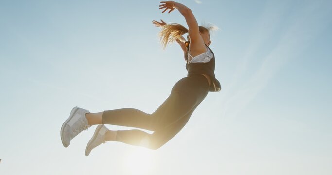 A Dynamic Jumping Woman Exuding Energy Against a Beautifully Clear Sky Above Her