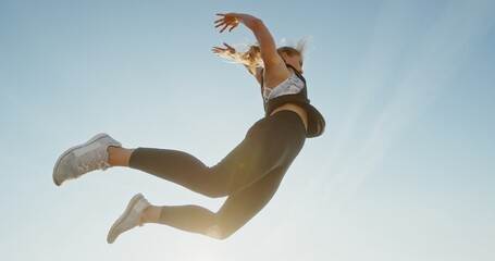 Dynamic Jumping Woman in Stylish Athletic Gear Beneath a Bright and Clear Sky Above