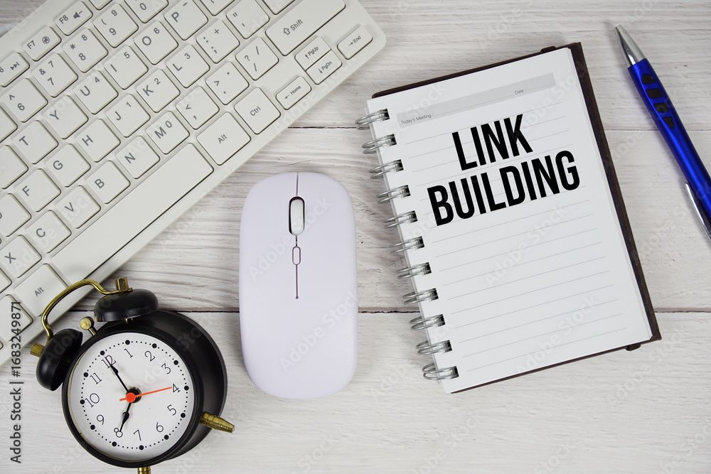 Aufkleber link building text with alarm clock, keyboard and wireless mouse on wooden background